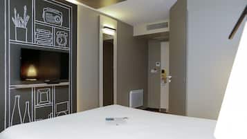 Ein Hotelzimmer mit einem Bett, einem Flachbildfernseher, einer Tafel mit Zeichnungen, einer Heizung und einer Tür zu einem anderen Zimmer.