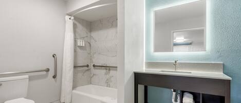 A bathroom with a toilet, a shower with a curtain, a bathtub, and a vanity with a mirror.