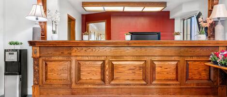A reception desk with a wooden finish, a water dispenser, and a sign reading 'RED LION HOTELS SONESTA'.