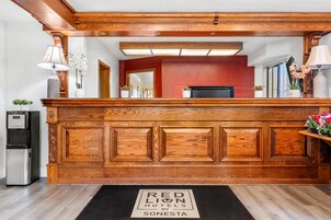 Un comptoir d’accueil avec un revêtement en bois, un distributeur d’eau et une enseigne indiquant « RED LION HOTELS SONESTA ».