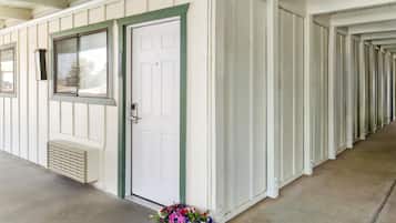 Una hilera de cabañas blancas con puerta y ventana verde, un respiradero y un arreglo floral en la entrada.