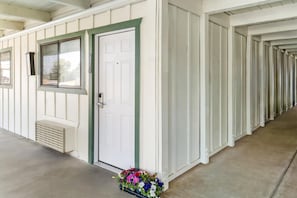 A row of white cabins with a green door and window, a vent, and a flower arrangement at the entrance.