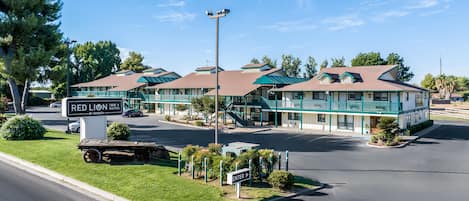 Un motel con un cartel, edificios de varios pisos y un área de estacionamiento.