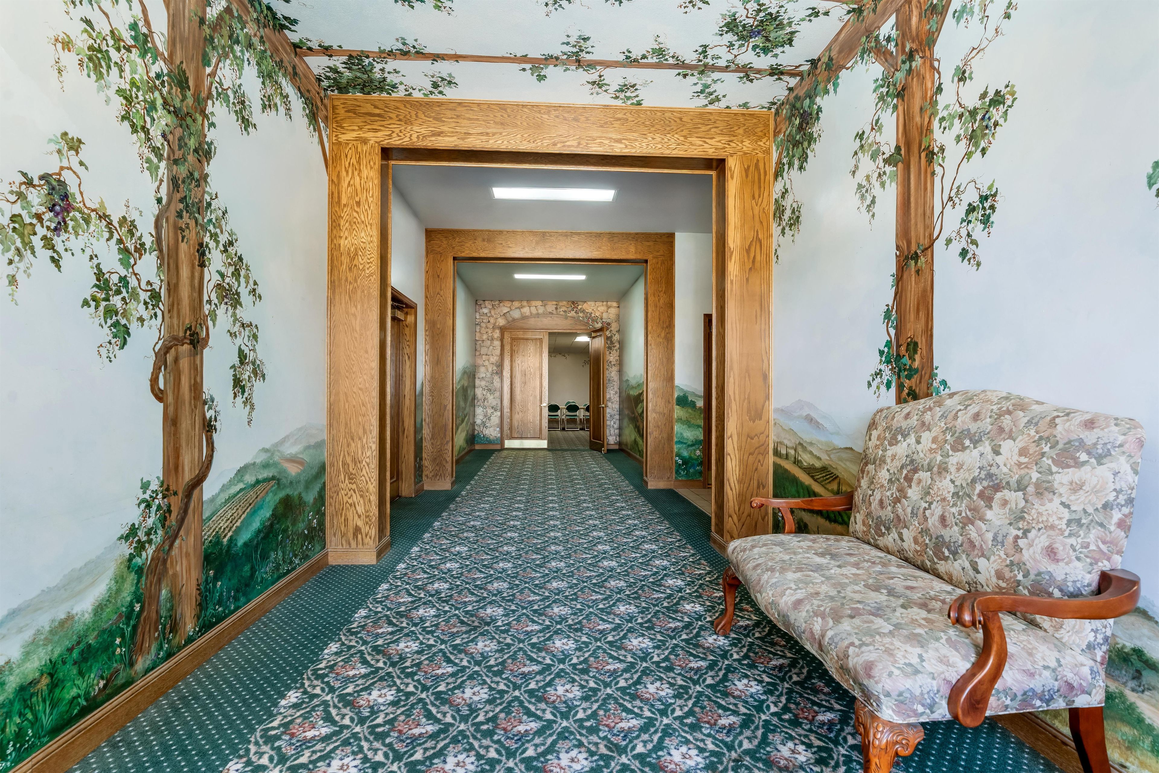 A hallway with a patterned carpet, wooden door frames, and a chair with a floral upholstery.