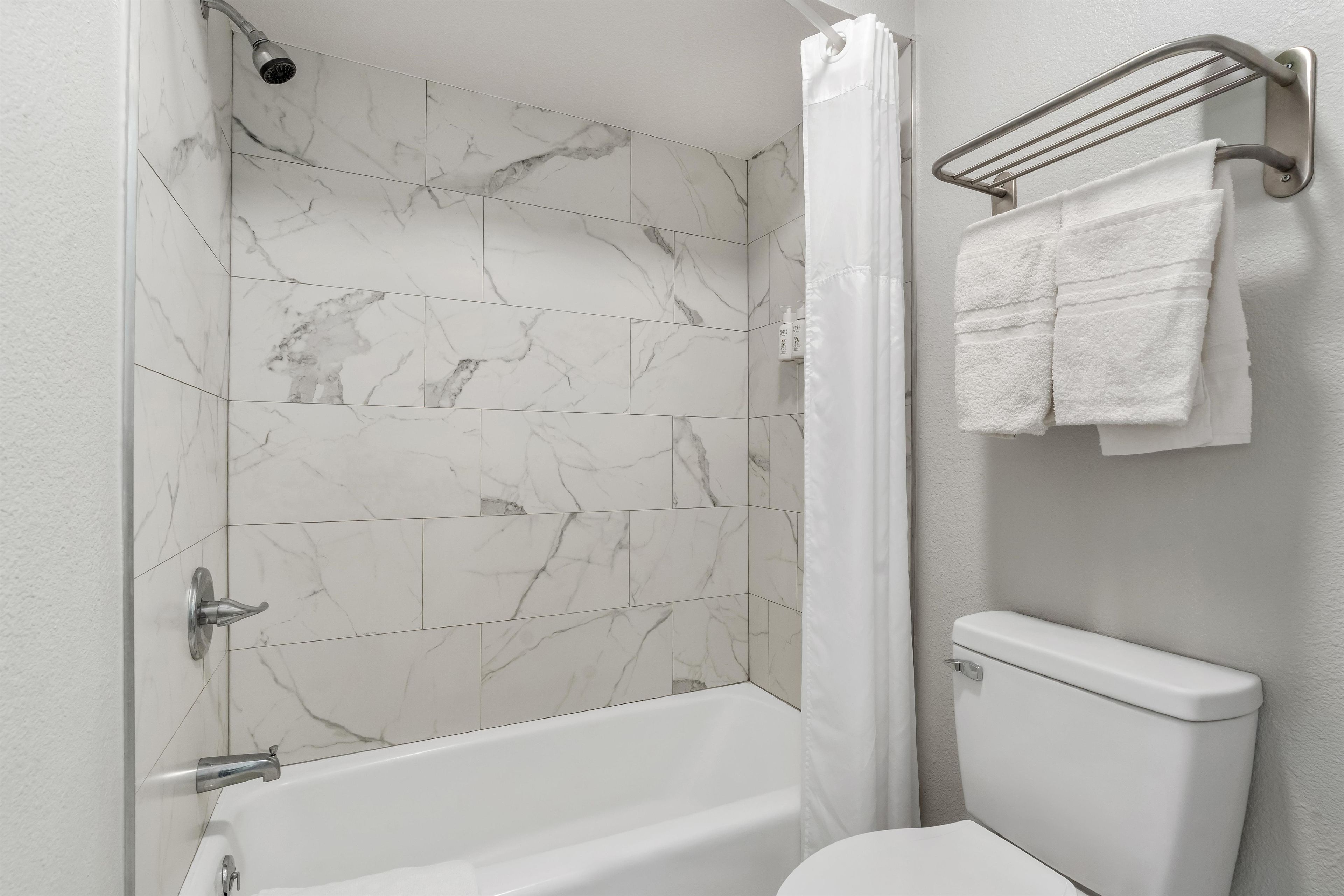 A bathroom with a bathtub, a toilet, and a shower curtain.