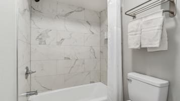 A bathroom with a bathtub, a toilet, and a shower curtain.
