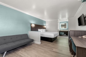 Una habitación de hotel moderna con una cama, un sofá, un escritorio y un televisor.