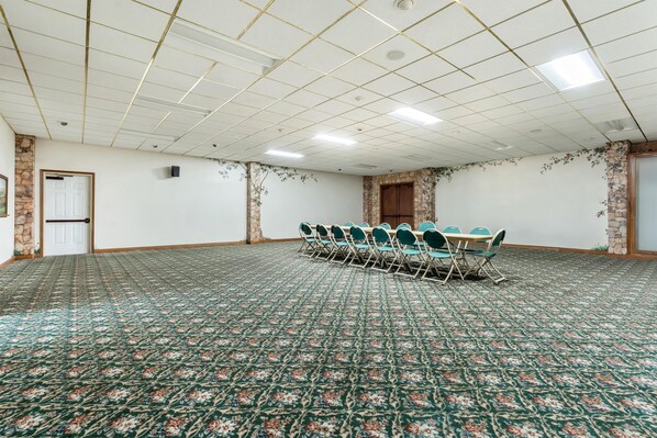 Una sala de conferencias con alfombra estampada, una mesa larga con sillas y una pared de acento de piedra.