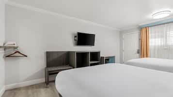 A hotel room with two beds, a TV mounted on the wall, a desk with a chair, and a wardrobe.