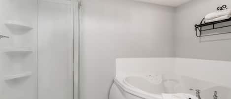 Un baño moderno con cabina de ducha de vidrio, bañera independiente y toallero en la pared.