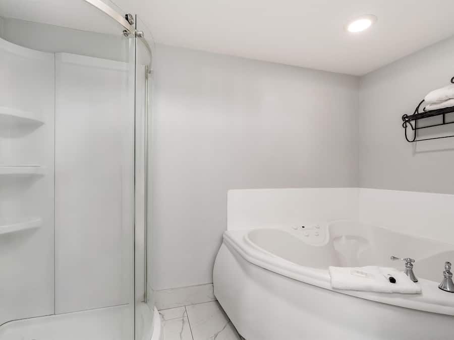 A modern bathroom with a glass shower enclosure, a freestanding bathtub, and a towel rack on the wall.