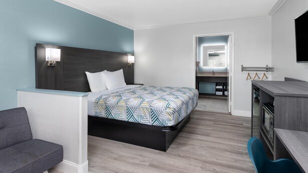 Una habitación de hotel moderna con una cama, un escritorio, una silla y un televisor.