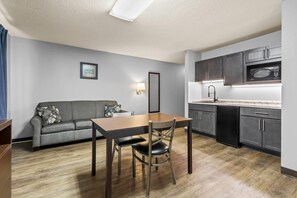 A compact kitchen with dark cabinets, a microwave, and a dining area with a table and chairs. - Park Inn by Radisson (Ortonville)