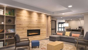 A modern living room with a fireplace, a sectional sofa, a coffee table, and a bookshelf. - Country Inn & Suites by Radisson, La Crosse, WI (La Crosse)
