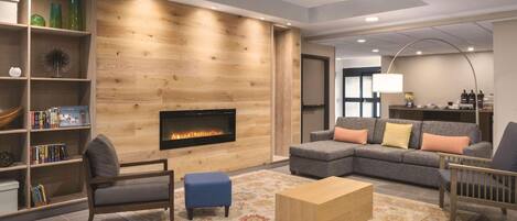 Una sala moderna con chimenea, sofá modular, una mesa de centro y una estantería.