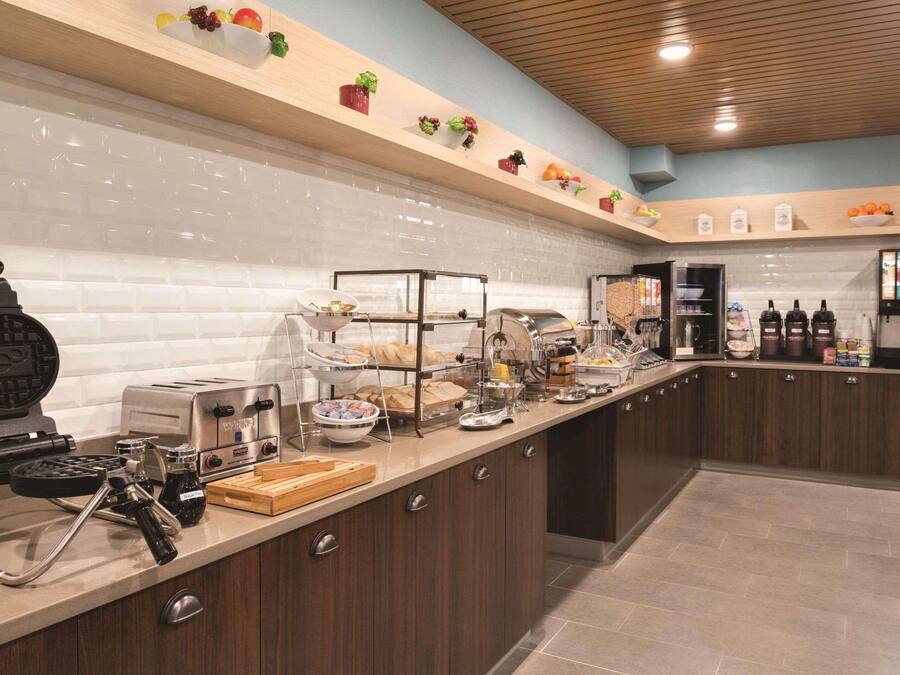 Una cocina moderna con una máquina para hacer gofres, una tostadora y diversos alimentos sobre la encimera.