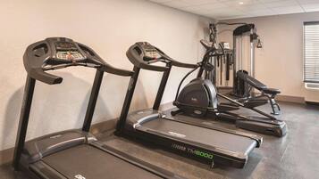 Un gimnasio con cintas de correr, elípticas y equipo de pesas.