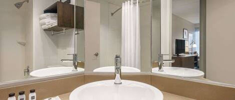 A bathroom with two sinks, a shower, and a mirror.