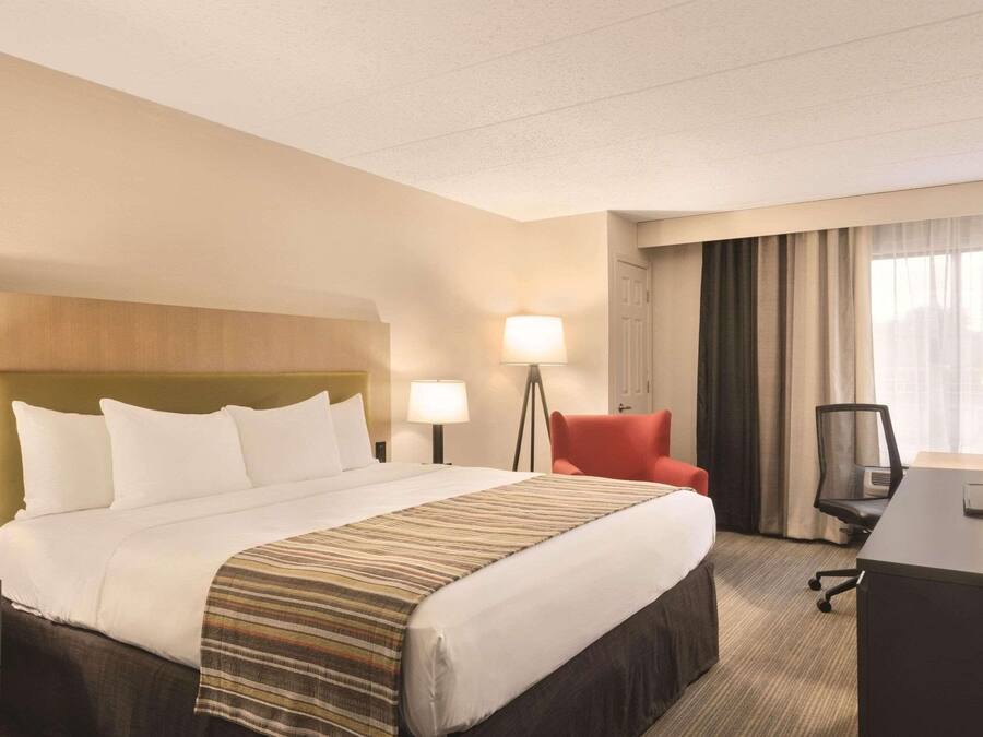 Une chambre d’hôtel avec un grand lit, un bureau, une chaise, une lampe et un téléviseur.