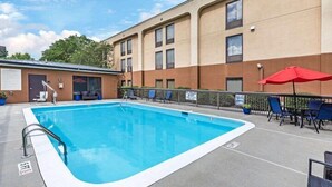 A swimming pool with a metal ladder, lounge chairs, and umbrellas.