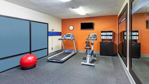 A fitness room with a treadmill, elliptical, and a red exercise ball.