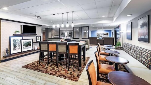 A modern dining area with a central island, multiple seating options, and a flat-screen TV mounted on the wall.