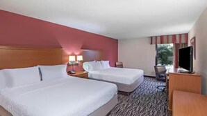 A hotel room with two beds, a desk, a chair, a TV, and a window with curtains.