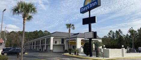 A Days Inn hotel with a parking lot, palm trees, and a clear sky.