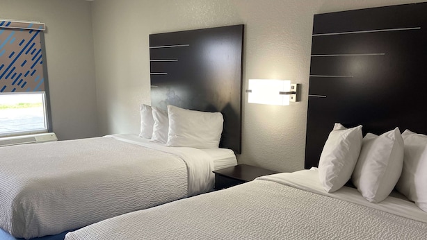 Une chambre d’hôtel avec deux lits, chacun étant équipé de draps blancs et d’une tête de lit.