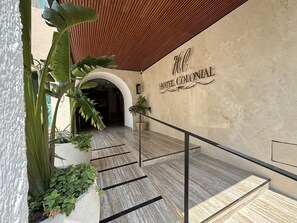 Un vestíbul d'hotel amb sòl de marbre, sostre de fusta i un rètol que diu "HOTEL COLONIAL".