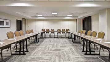 Un salón de conferencias con una larga mesa, sillas y cristalería.