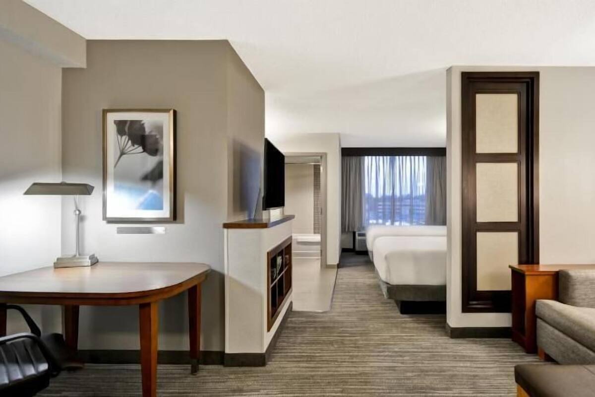 Habitación de hotel con escritorio, televisión, sofá y cama.
