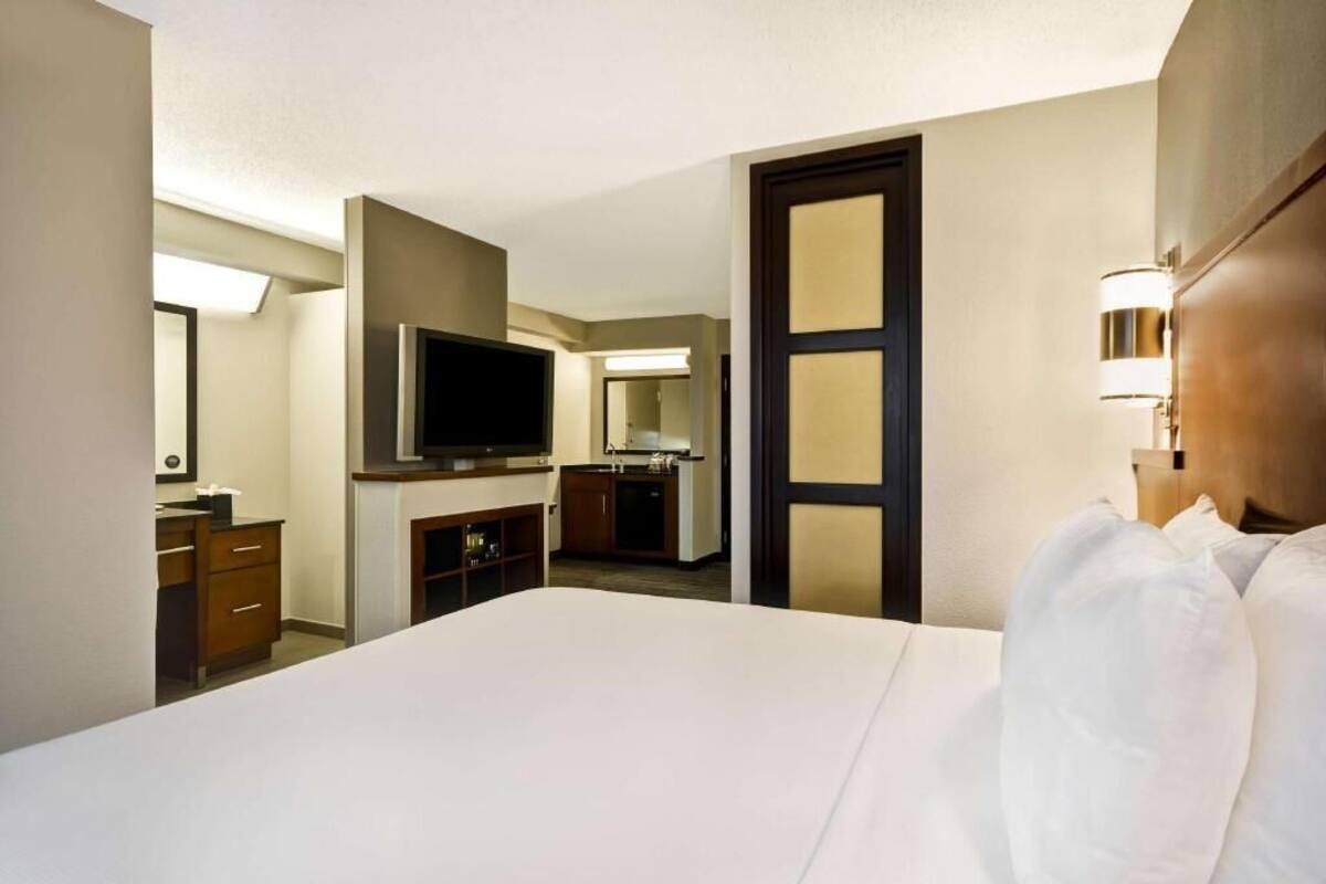 Una habitación de hotel con cama, televisión, escritorio y espejo.