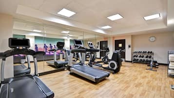A gym with treadmills, elliptical machines, and a mirror wall.