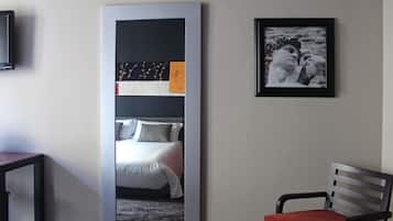 Una camera d'albergo con un letto, una sedia e un'ampia opera d'arte appesa al muro.