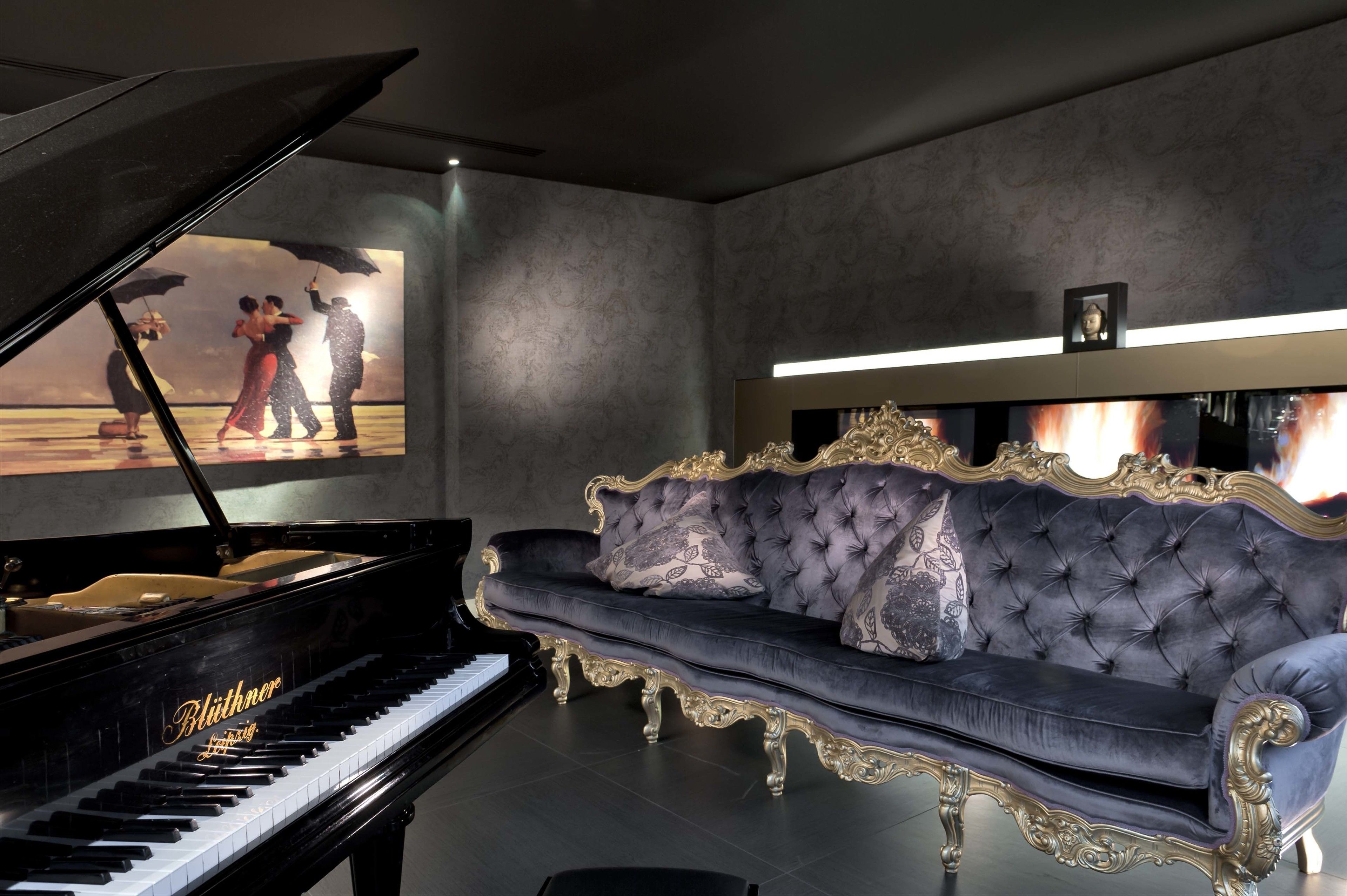 Un pianoforte a coda, un divano trapuntato e un'opera d'arte incorniciata appesa al muro.