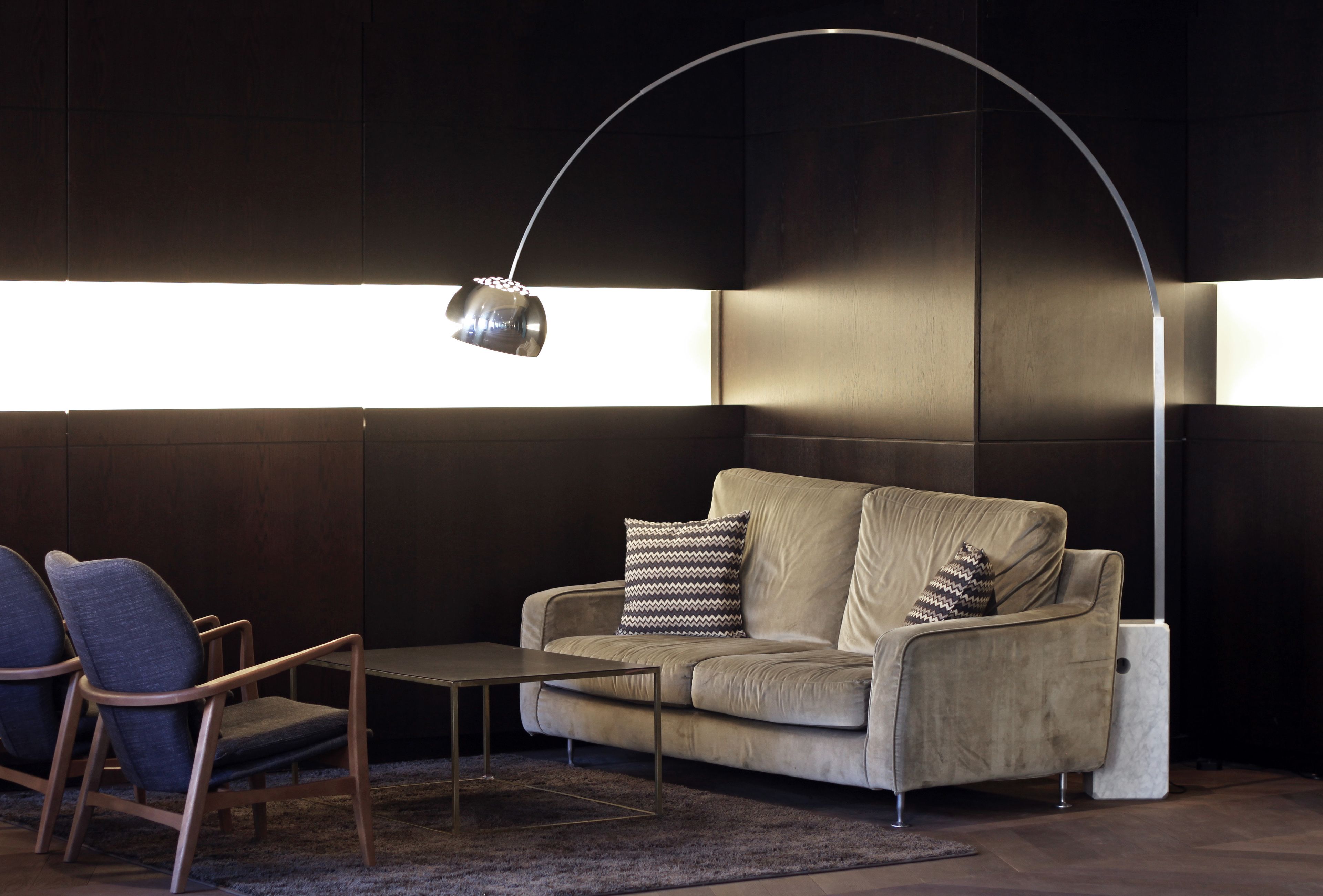 Una sala de estar moderna con un sofá, dos sillones, una mesa de centro y una lámpara de pie.