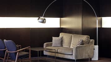 Una sala de estar moderna con un sofá, dos sillones, una mesa de centro y una lámpara de pie.