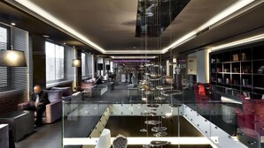A modern hotel lobby with a glass coffee table, seating areas, and a bookshelf. - c-hotels Ambasciatori (Florence)