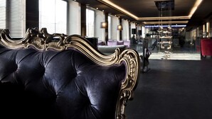 A luxurious room with a plush dark blue upholstered sofa, ornate gold detailing, and a modern chandelier. - c-hotels Ambasciatori (Florence)