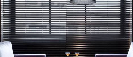 A modern room with two armchairs, a central coffee table, and a large window with horizontal blinds.