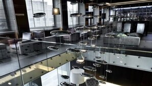 A modern interior with a glass railing, hanging pendant lights, and a seating area with a unique chair design. - c-hotels Ambasciatori (Florence)
