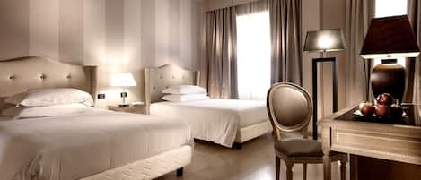 A hotel room with two beds, a desk with a lamp, and a chair.