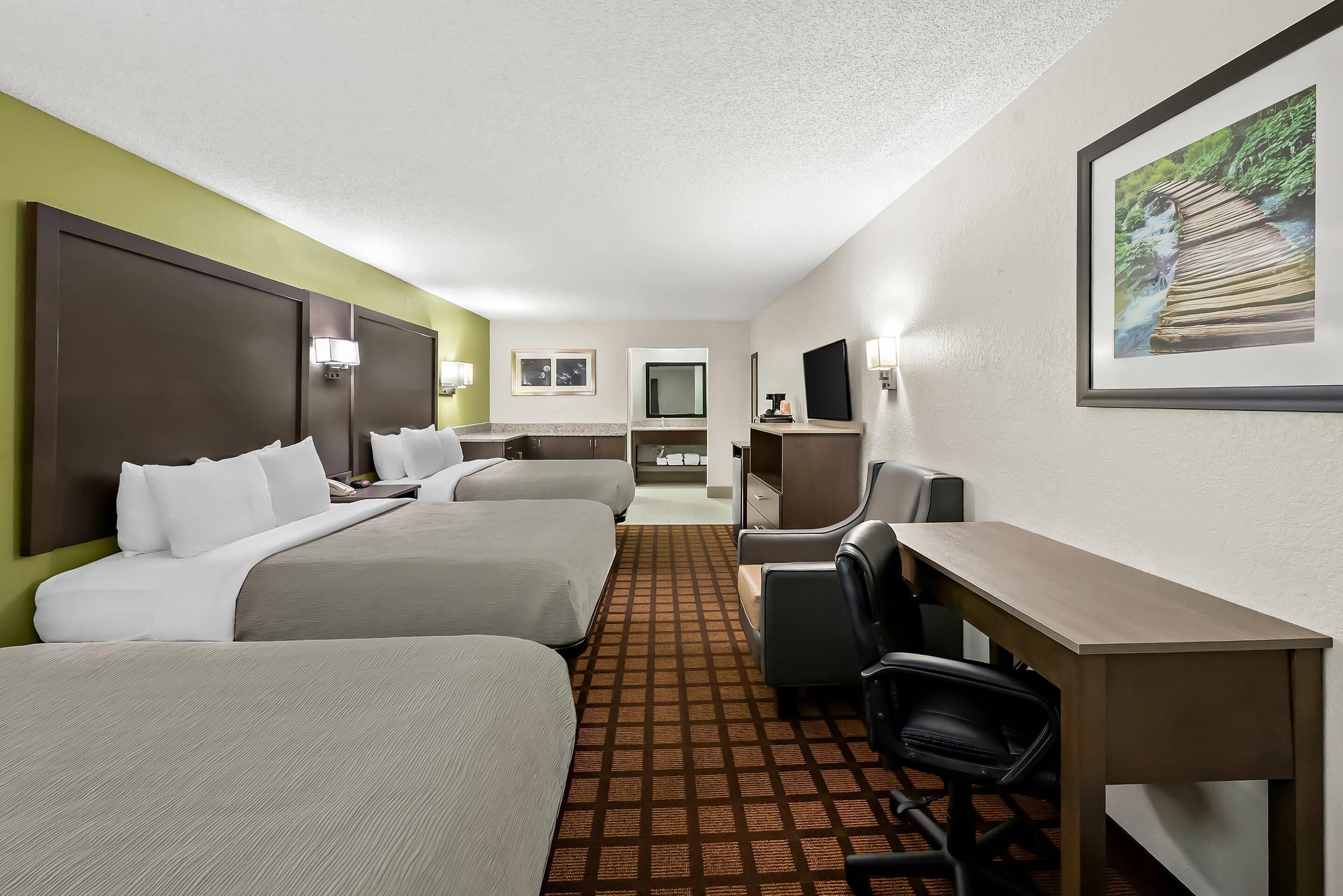 A hotel room with two beds, a desk, a chair, a television, and a framed picture on the wall.