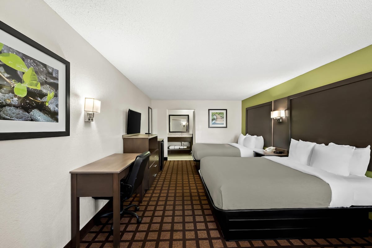 Ein Hotelzimmer mit Bett, Schreibtisch, Stuhl und einem kleinen Badezimmer.