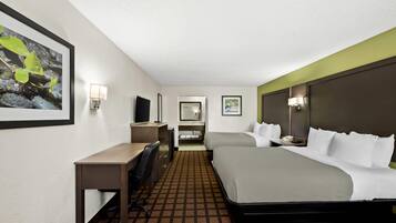 Una habitación de hotel con cama, escritorio, silla y un baño pequeño.