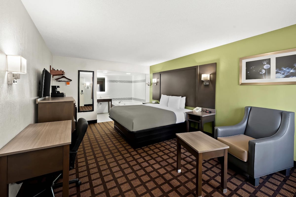 Ein Hotelzimmer mit Bett, Schreibtisch, Stuhl und einem kleinen Tisch.
