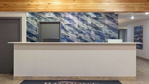 Un mostrador de recepción con un revestimiento de pared con diseño de mármol, techo de madera y un letrero de Baymont Inn & Suites.