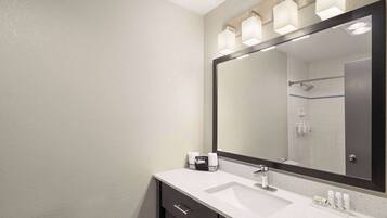 A bathroom with a large mirror, a sink, and a towel rack.