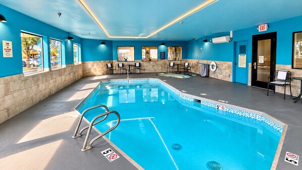 An indoor swimming pool with clear lane markings, a lifeguard chair, and a poolside area with chairs and tables. - Baymont by Wyndham Moses Lake (Moses Lake)